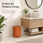 Terracotta square pedal trash can placed in a modern bathroom next to a floating vanity